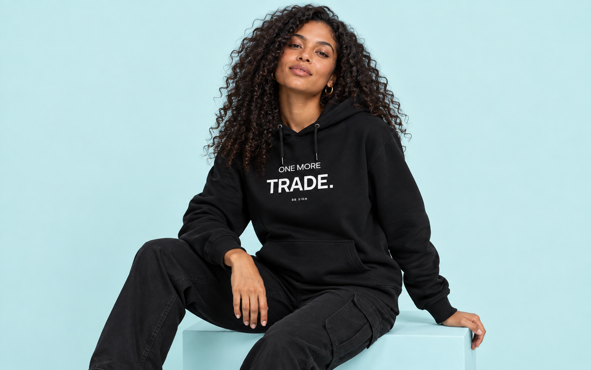 Model wearing the One More Trade hoodie against a soft cyan studio backdrop